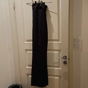 Svarta kostymbyxor med högmidja. Byxorna är av dwn tunnare varianten och har dragkedja, hake samt knytskärp. byxorna är i fint använt skick.