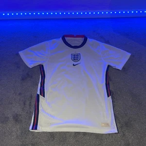 England fotbollströja - Säljer en England tröja som köptes i somras för 900. Tröjan är inte använd så mycket eftersom den blev för liten. Dyraste versionen av fotbollströjor. Några defekter. Skriv för fler bilder