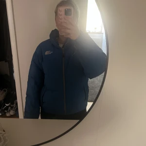 The North Face jacka - Jacka från the North Face, mycket unik blå färg med vita detaljer. Har en defekt på armen men inget som stört mig/går nog att sy igen. Annars en färg som inte finns att få tag på. Har aldrig testat tvätta den men kan behövas vid köp!