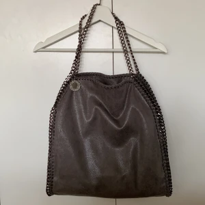 Stella McCartney liknande flabella väska - As snygg grå skimrig fake stella McCartney väska flabella i den stora modellen. Tillkommer liten neccesär i väskan. Så himla snygg. Knappt använd🔥