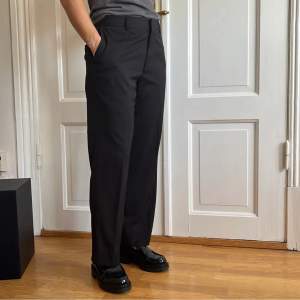 Svarta kostymbyxor med klassiska små vita ränder. Pasar till någon som är ca 160 cm lång och har 34-38 i storlek. 