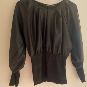 Stilig blus - Blus som är pösig för att sedan sitta tajt längs underarm samt midja. Två olika material på tröjan som ni ser på bilderna. Inga defekter.