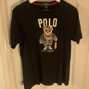 Svart t-shirt med tryck från Ralph Lauren - Svart t-shirt med tryck från Ralph Lauren. Storlek XL för barn (passar 18-20 år)! Fint skick!