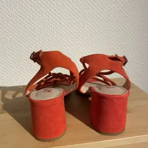 Helt oanvända sandaletter i en superfin orangeröd färg. Passar dig som har en smal/liten 36a.   I äkta mocka! 