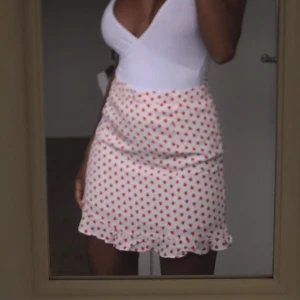 Kjol med röda hjärtan  - Säljer denna super fina kjolen som är perfekt till sommaren. Den har volanger nertill och är täckt av röda hjärtan. Köparen står för frakten 