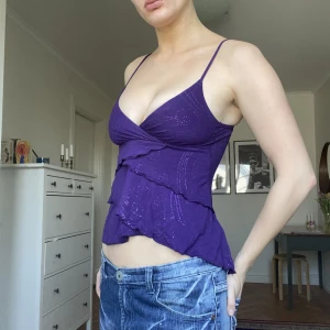 Volanglinne lila - Lila volanglinne (topp) ifrån BAY. Storlek S. Lite glitter på volangerna. Inga defekter :)