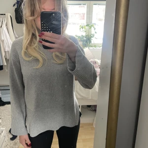 Stickad tröja  - Stilren grå stickad tröja med slits och långa och breda armar