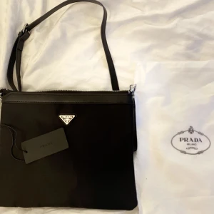 Prada Messenger Nylon Bag - Säljer denna fina prada väska vilket jag fick i födelsedagspresent. Köpt i london från butiken MATCHES FASHION.  Tyvär inga kvitton Säljer för över 7000kr ny!