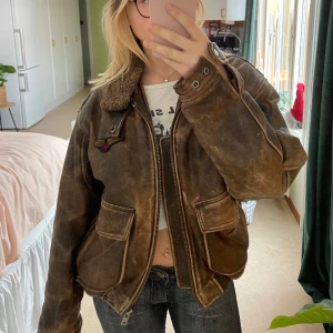 Skinnjacka TopGun - Original skinnjacka från 1989, inspirerad från filmen TopGun. Endast en ägare (min pappa). Originalpris 6000kr. Säljer pga för stor annars skitsnygg🤩 pälsen på kragen går att ta av med dragkedja och under är vanlig skinnkrage!