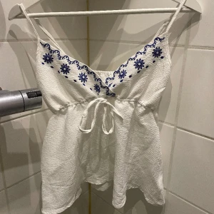 Söt topp - Söt vitblommig topp från SHEIN i stl s🙌🏻aldrig använd och säljer pga det. bra kvalitet och justerbara band! Köparen står för frakten!!💕💕