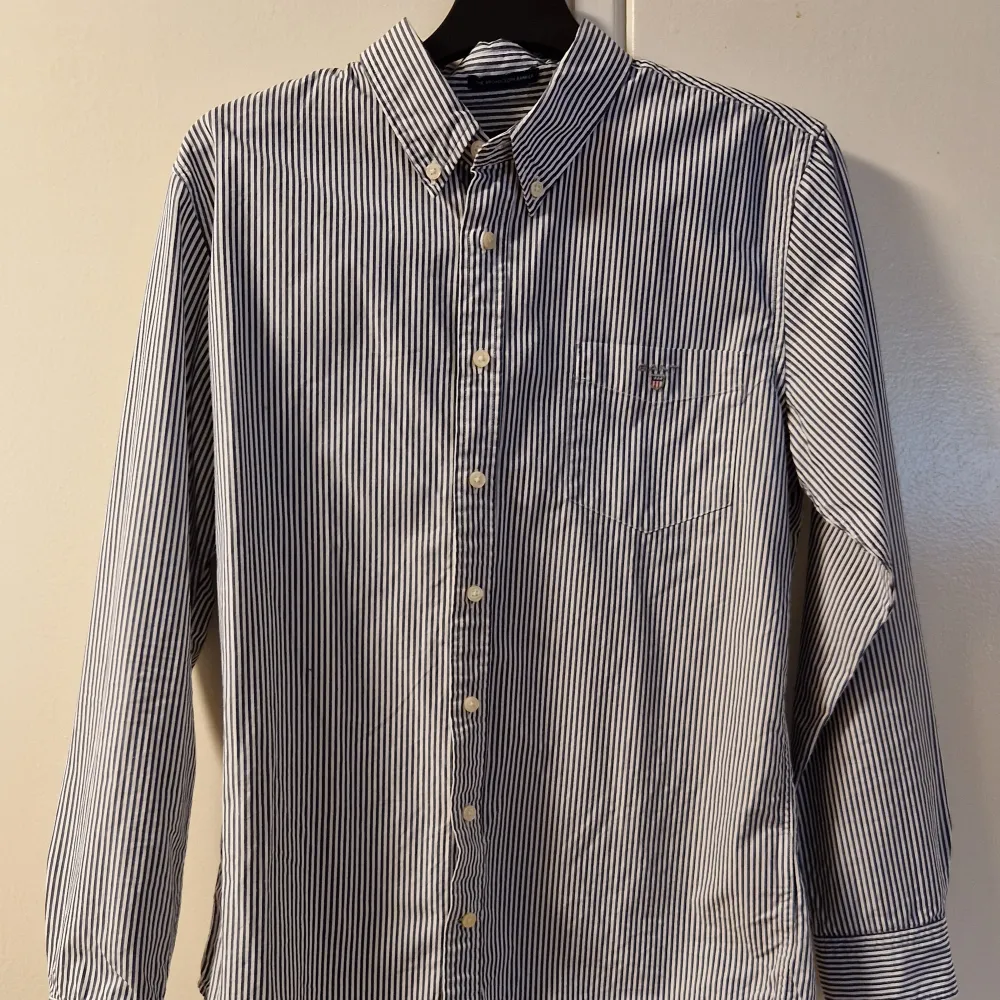 Säljer en blå/vit randig Gantskjorta eftersom att jag har växt ur den, väldigt sparsamt använd och har inga märken eller fläckar. Storlek: 170 vilket motsvarar xs, Skick: 9/10, Pris: 129kr, Nypris 700kr.. Skjortor.