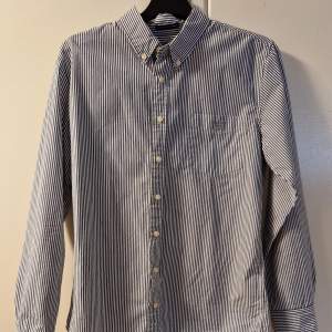 Säljer en blå/vit randig Gantskjorta eftersom att jag har växt ur den, väldigt sparsamt använd och har inga märken eller fläckar. Storlek: 170 vilket motsvarar xs, Skick: 9/10, Pris: 129kr, Nypris 700kr.