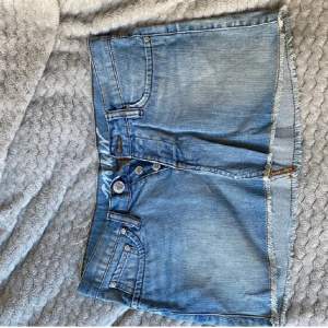 Vintage lågmidjad jeanskjol, fickor bak och fram, knäppning med 3 knappar, kortare modell, sitter tajt om du har lite större höfter 