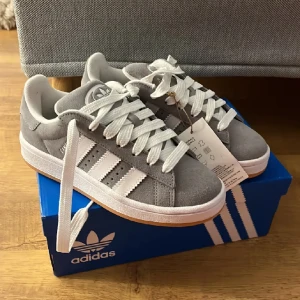 Adidas campus 00s - Säljer ett par Adidas campus 00s i grå då de va för små för mig. Skorna är aldrig använda därav är de i prima skick. Storlek 36. Både Låda och kvitto finns. Högsta bud gäller