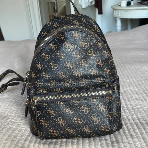 Liten guess ryggsäck - Äkta Guess ryggsäck köpt på Zalando för typ 4 år sen. Endast använd ett fåtal gånger så den är i super bra skick. Dust bag medföljer🤍🤍