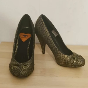 Högklackat - Högklackat med krockodilskins-liknande mönster. Ganska små för att vara storlek 36. Rätt bra skick. Har inte använt dom själv men fick dom begagnade.