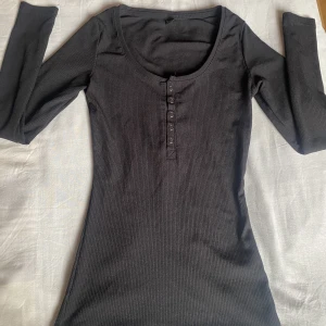 Svart tröja med knappar - Svart långärmad tröja med knappar som man kan öppna, Storleken är Xs och materialen är stretchig! 