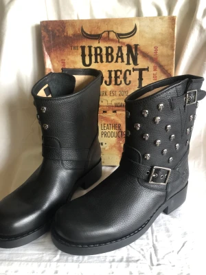 Urban project boots - Stl 40. Svarta läder Urban project stövlar/boots med dödskallar i metall. Oljebeständig sula, oanvända, originalkartong, nypris 1700 kr 