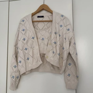 Stickat sett med blommor - Matchande stickad kofta och linne med blommor. Säljer koftan & linnet tillsammans för 200kr. 