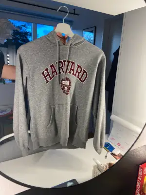 En grå hoodie från H&M med tryck ”Harvard” Vädligt skön och snygg, storlek XS passar nog S också. Hör av er vid frågor eller undringar 🩶🩶