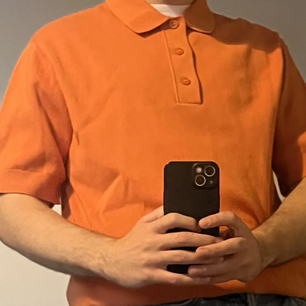 Hi! A short sleeved orange polo from COS. It is a small but fits a medium.  Only worn once and it is made of 100% cotton.. Toppar.