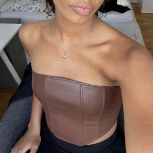Korsett topp brun  - Korsett topp i ”faux leather”. Frakten står köparen för.