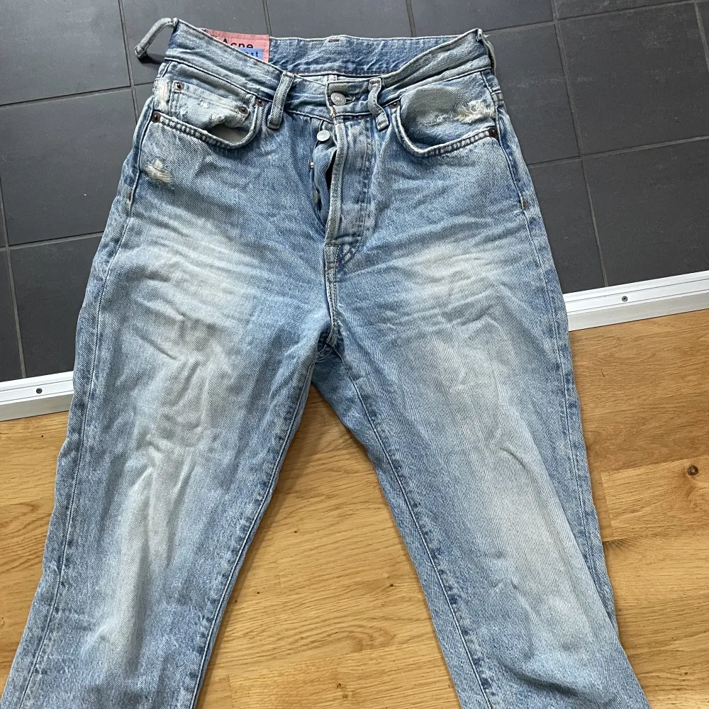 Ett par blåa snygga jeans från Acne. Jeansen är använda mycket och därför urtvättade och söndriga på ett ställe (syns på bild 2). Storlek  26/32, 165/66A. . Jeans & Byxor.