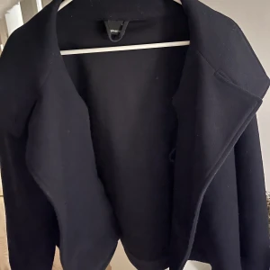 Kort kappa - Säljer min jättefina kappa från Gina tricot! Den är marinblå och har knappar så att man kan stänga den. Köptes i våras för 600kr. Använd men inga defekter, utan är som ny! Storlek S💕