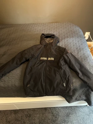 Napapijri jacka st170 - Aldrig använd köptes i fel storlek. St 170 i svart färg. Perfekt regn jacka eller vind jacka nu till hösten.