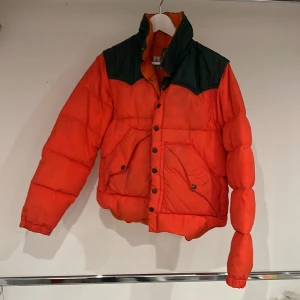 Retrotäckjacka - Mattes mammas gamla täckjacka från 70-talet. Orange med mörkgrönt förstärkt axelmakterna. Tight fit. Vild du vara varm och samtidigt sticka ut är detta plagget för dig. 😸