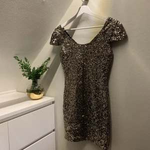 Paljettklänning - Guldig paljettklänning från Dennis Maglic. Perfekta nyårs och festklänningen! Endast använd en gång. Paljetterna sitter bra så de trillar inte av under kvällen :)