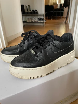 Nike air AF1 black/white strl 37.5 - Nike Air AF1 sneakers black/white. Storlek 37.5. Nypris 1455 kr.  Mer info: https://www.zalando.se/nike-sportswear-af1-pltaform-sneakers-blackanthracitewhite-ni111a125-q11.html  Skona är hela och rena, förutom att sulan gulnat är de i gott skick