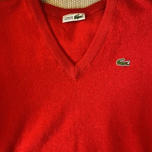 Stickad Lacoste tröja - Röd, stickad tröja från Lacoste. Tröjan är i fint skick, och i mjukt och lyxigt material.  Vid intresse är det bara att skriva och fråga om pris osv :)