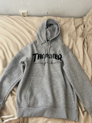 Thrasher Hoodie Grå - Säljer denna gråa thrasher hoodien då den blivigt för liten för mig Storlek M, passar baggy om man har S Köpt på Junkyard, kostar 1100kr nypris