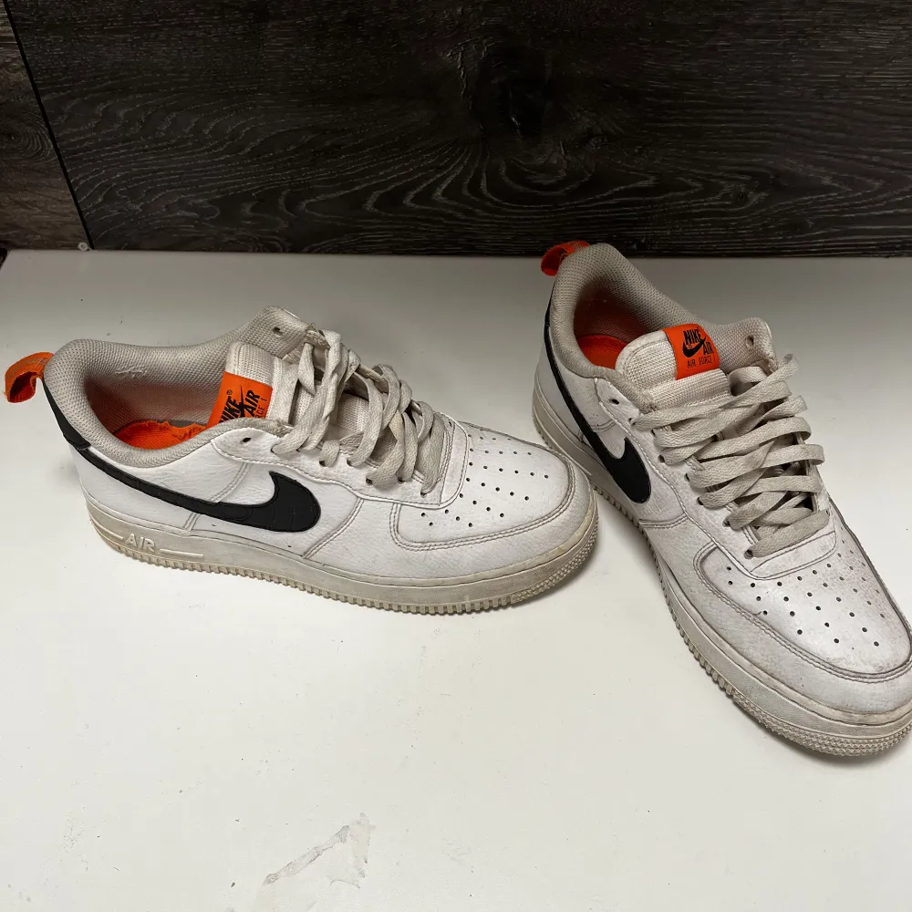 Vita Nike air force med svarta och orange detaljer. Skorna är använda men i bra skick.. Skor.
