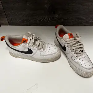 Vita Nike air force med svarta och orange detaljer. Skorna är använda men i bra skick.