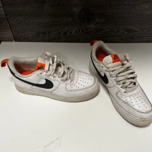 Nike air Force vita - Vita Nike air force med svarta och orange detaljer. Skorna är använda men i bra skick.