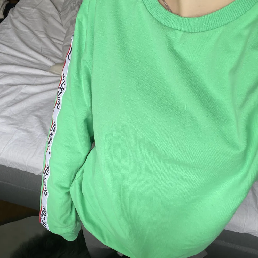 Säljer min brors gröna Moschino sweatshirt med detaljer längst ärmarna. Den är i herr storlek men är en unisex tröja, alltså till för både tjejer och killar. Nypris ca 2500kr. Pris går att diskuteras! Skriv privat för fler bilder! 😊. Hoodies.