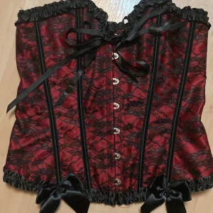Korsett - Vinröd korsett med spets detaljer och rosetter fint skick aldrig använd går att pruta