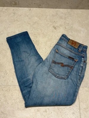 Nudie Jeans - Säljer dessa snygga Nudie Jeans i modellen Grim Tim | Jeansen har en fin ljusblå färg med snygga fades | Storlek 28/32 | Jeansen är i bra skick men har en defekt i form av en fläck på ena knät (se sista bild) | Hör av er vid funderingar eller prisförslag |