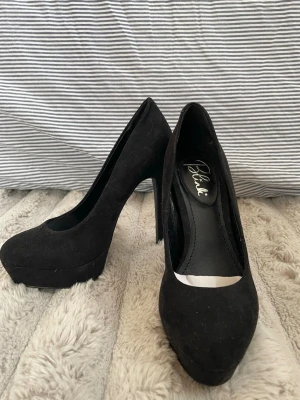 Svarta pumps - Snygga svarta pumps med hög klack och platåsula i mockaimitation. Klassisk rund tå och stilren design som passar till många olika outfits. Perfekta för dig som vill ha lite extra höjd och en elegant look.