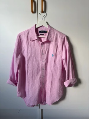 Rosa Ralph Lauren Skjorta - Säljer en rosa Ralph lauren skjorta då den är för stor på mig. Skjortan har inga defekter och ärmarna går att rulla ut till normal längd. Priset är inte hugget i sten, hör av er vid frågor! 🐎 