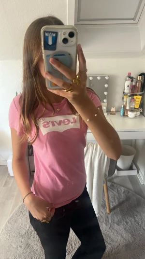 Rosa Levi's t-shirt med logga - Säljer en rosa t-shirt från Levi's med den klassiska loggan tryckt i vitt på bröstet. T-shirten är kortärmad och har en normal passform. Perfekt för dig som gillar en enkel men snygg stil.