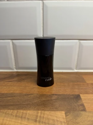 Armani Code parfym 50 ml - Armani Code parfym i en elegant svart flaska med stilren design och rundad form. Flaskan rymmer 50 ml och har en matt svart kork. Perfekt för dig som gillar exklusiva dofter och vill ha en klassisk parfymflaska i badrumsskåpet. Skulle nog gissa att 35-45 ml är kvar i den.