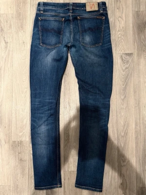 Nudie Jeans Skinny Lin Blå W31/L32 - Slim/Skinny Fit - Nudie Jeans Skinny Lin ”Navy Mist” blå jeans med slim/skinny passform, normalhög midja och smala, avsmalnande ben, storlek W31/L32, midja 40 cm, ytterbenslängd 107 cm, benöppning 15,5 cm, modellen är 185cm & väger 65kg, i fint skick.
