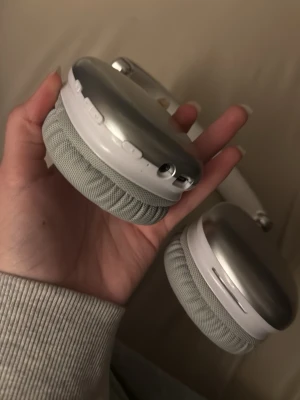 Stilrena silverfärgade over-ear hörlurar - Snygga over-ear hörlurar i silver med mjuka, grå tygkuddar och metallisk finish. De har en modern, fyrkantig design och vadderad bygel för extra komfort. Perfekta för att lyssna på musik eller poddar med stil.