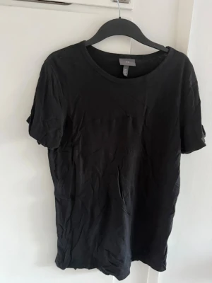 Svart basic t-shirt i bomull - En enkel svart t-shirt med rund hals och korta ärmar. Tillverkad i mjuk bomull och har en klassisk passform som funkar till allt. Perfekt basplagg för garderoben.