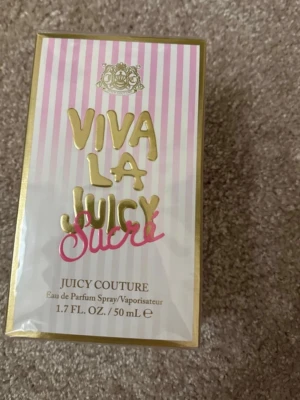 Viva La Juicy Sucré parfym 50 ml - Viva La Juicy Sucré från Juicy Couture är en Eau de Parfum på 50 ml. Förpackningen har rosa och vita ränder med gulddetaljer och text i guld och rosa. Parfymen kommer i en lyxig kartong med elegant design och passar perfekt för dig som gillar söta dofter.