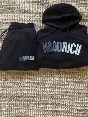 Hoodrich dress - Säljer en svart hoodie från HOODRICH med stor logga i vitt och grått på bröstet. Hoodien har huva med dragsko och en stor magficka. Perfekt för en chill och street-inspirerad look. Materialet är mjukt och skönt bomullstyg. Jag säljer också mina Hoodrich byxor till detta, jag köpte detta sett för 1799kr och säljer de nu för 799kr mycket bra pris inte använd mycket alls!