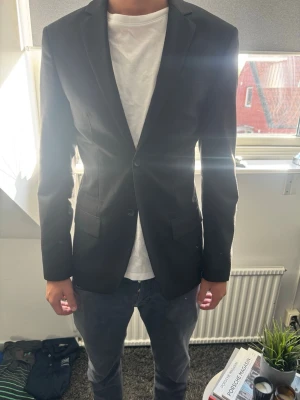 Filippa K kavaj - HELT NY! Snygg svart Filippa K kavaj i utmärkt skick - använd 1 gång. Strl 46 vilket motsvarar Small men passar mig som har Medium också. Nypris 3400kr. Modellen är 182cm och väger 65kg